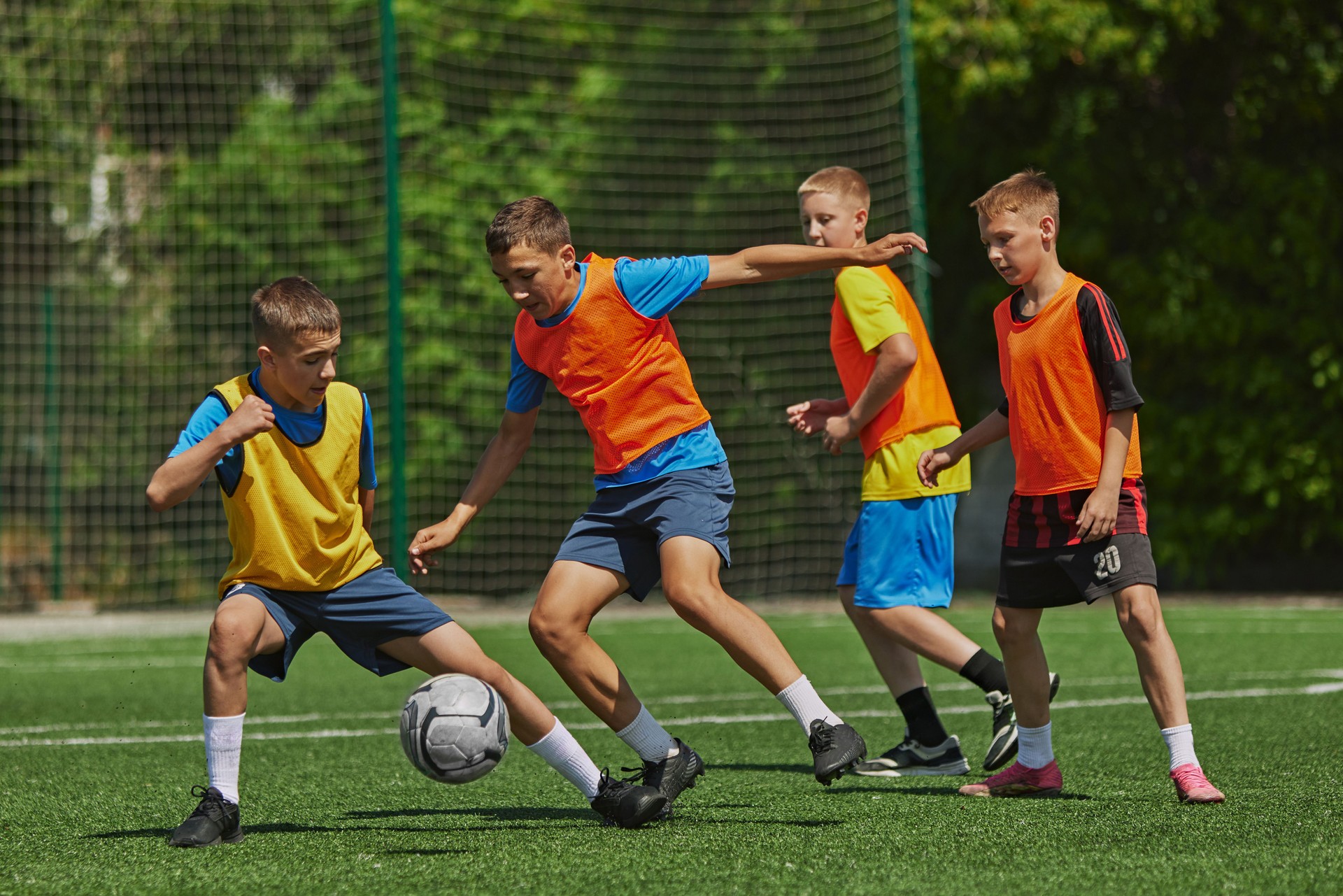 Sport and Strategy. Group of boys in motion, playing football game with concentration and motivation, competing with each other. Outdoor field